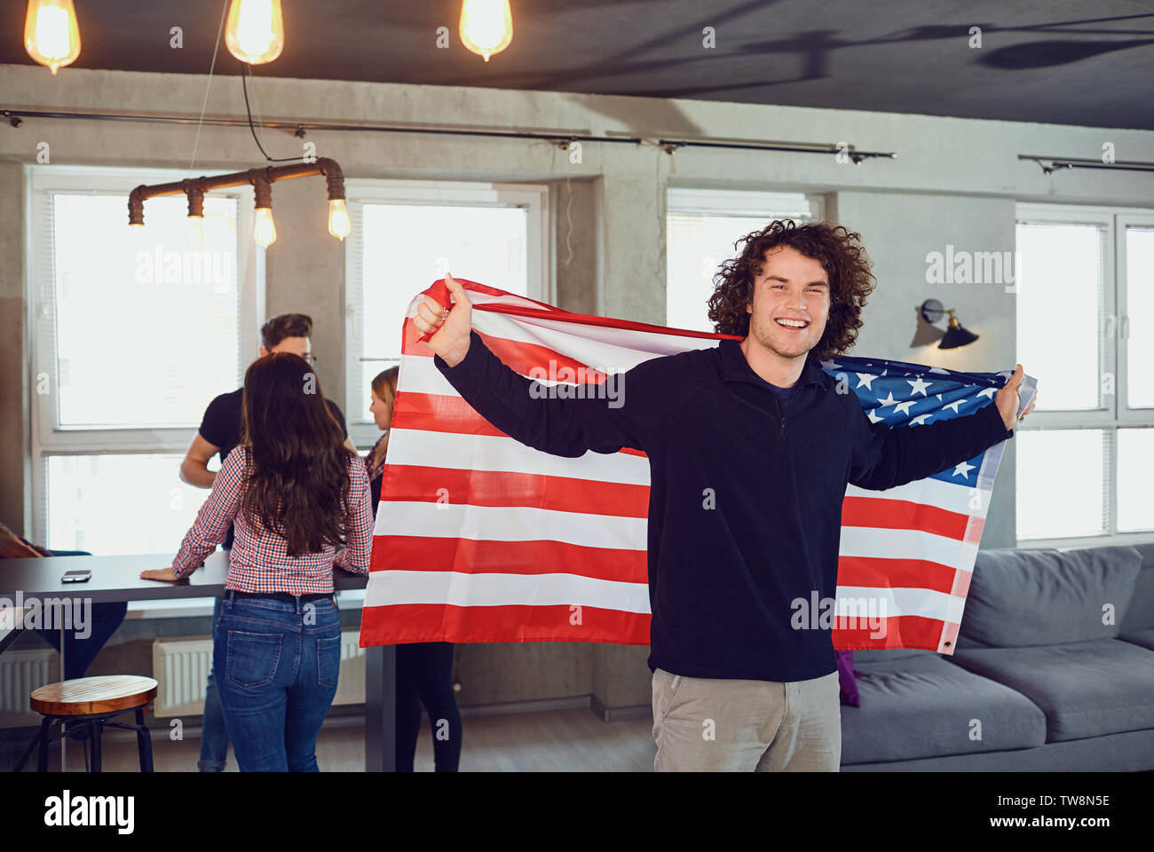 Kerl mit einem wunderschönen Lächeln mit der Flagge von Amerika im Innenbereich. Stockfoto Kerl mit einem wunderschönen Lächeln mit der Flagge von Amerika im Innenbereich. Stockfoto