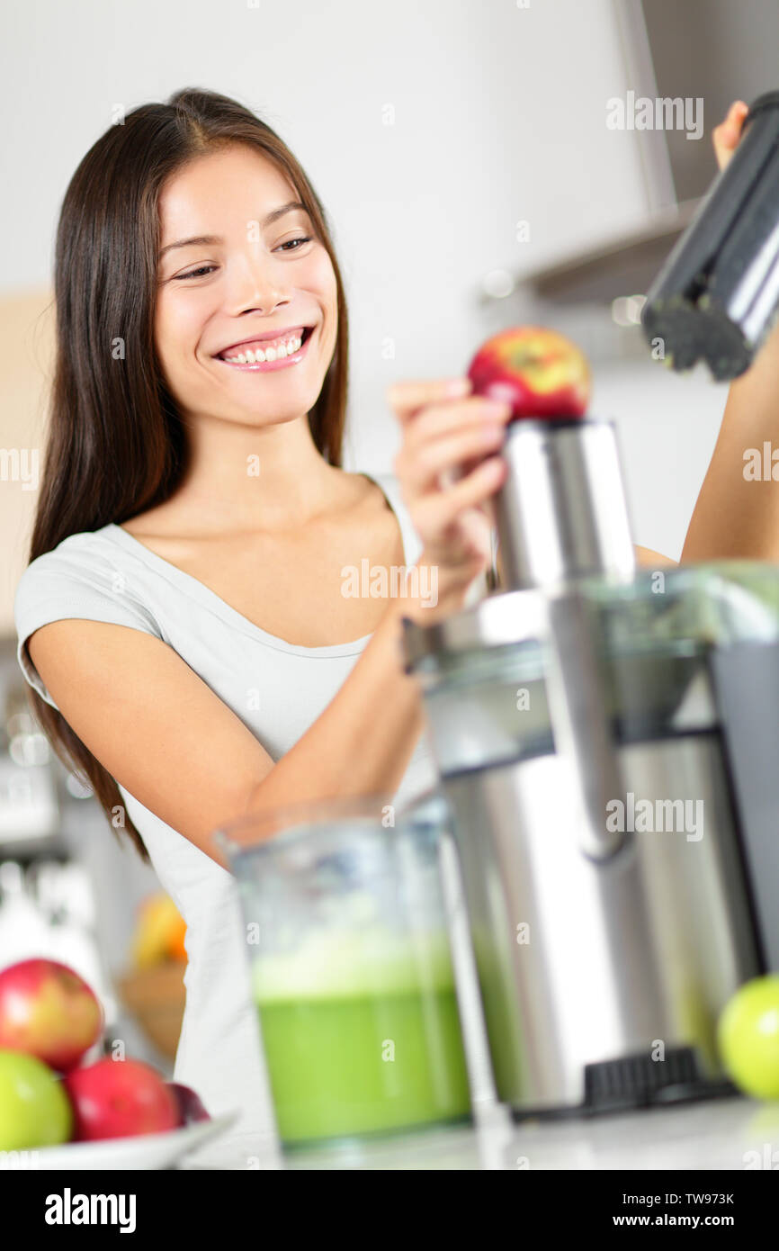 Frau macht Apple und gemüse saft Entsafter Maschine zu Hause in der Küche. Entsaften und gesundes Essen glücklich Frau, grünes Gemüse und Obst Saft. Gemischte Rasse asiatischen Kaukasischen Modell. Stockfoto