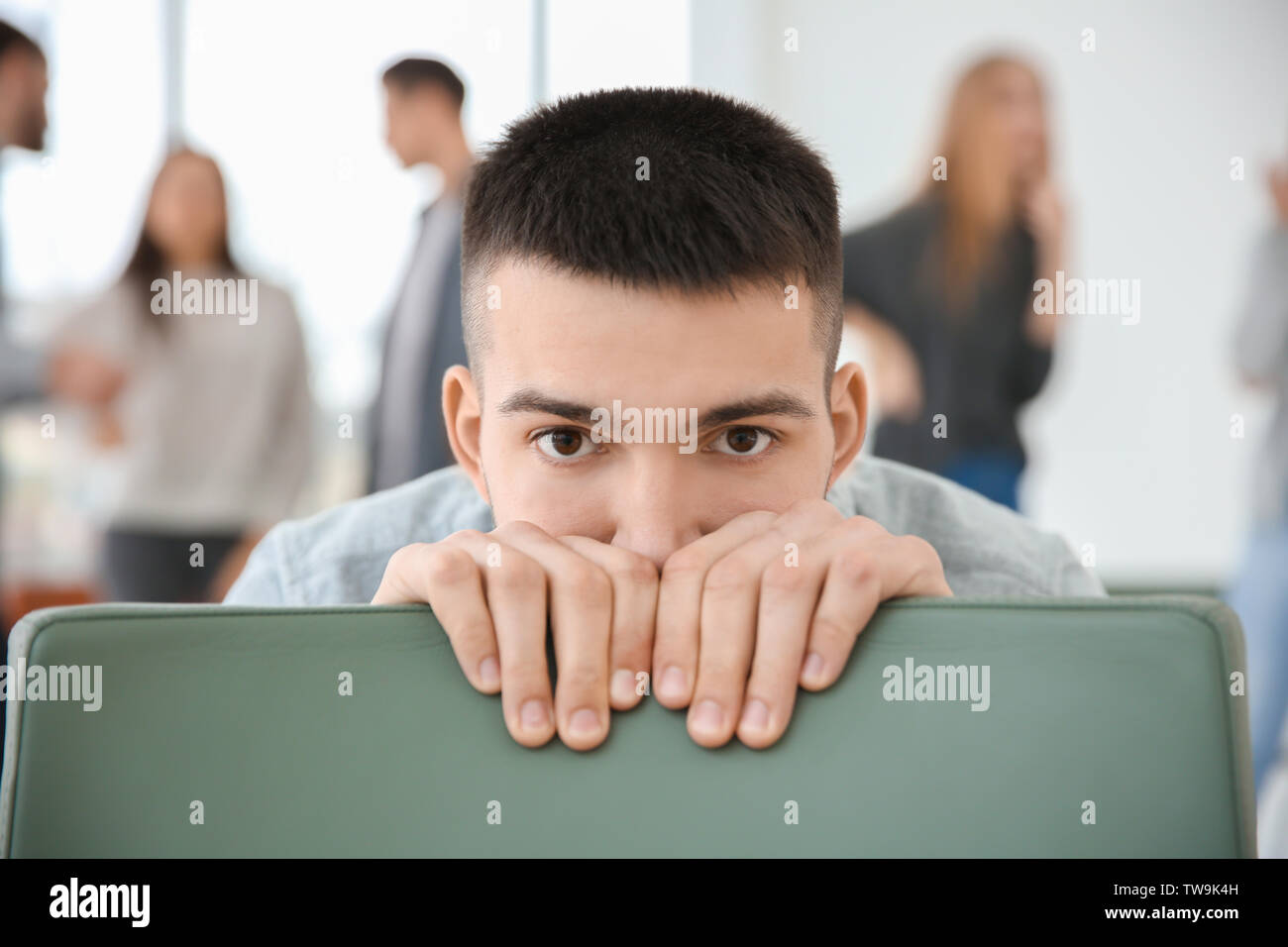 Man versteckt sich hinter Stuhl während der Gruppe Therapie, innen Stockfoto