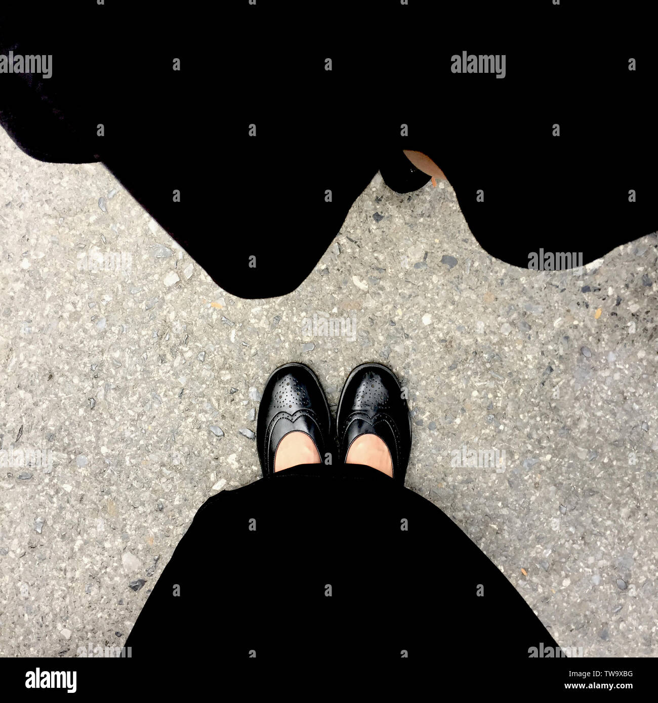 Schwarz High Heel auf Zement Hintergrund. Ansicht von oben schöne junge Frau mit schwarzen Schuhen auf Beton. Nahaufnahme der Beine und Füße für die Kleidung. Stockfoto