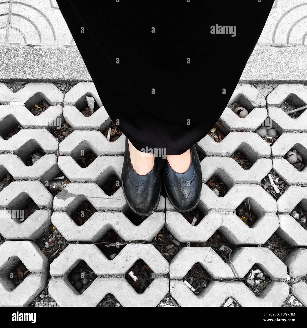 Frau Schwarz High Heel auf Zement Hintergrund tragen. Ansicht von oben schöne junge Frau mit schwarzen Schuhen auf Beton. Nahaufnahme der Beine und Füße für Kleidung Stockfoto