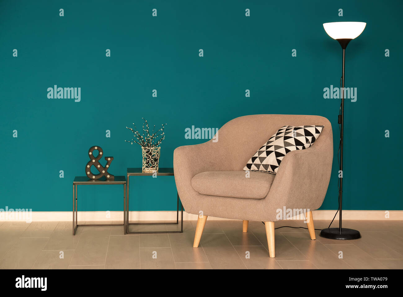 Trendy Sessel mit Lampe und Tabellen in der Nähe des schattigen Wand Fichte Stockfoto