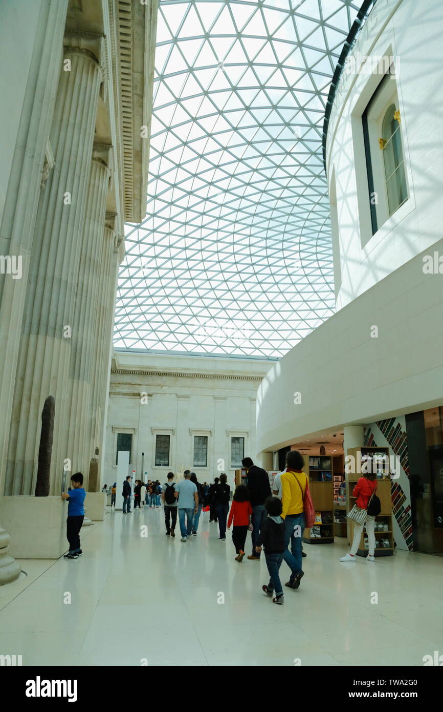 Eine Familie und Menschen gehen vorbei ein Shop in die Queen Elizabeth II Great Court des British Museum in London, Vereinigtes Königreich. Stockfoto