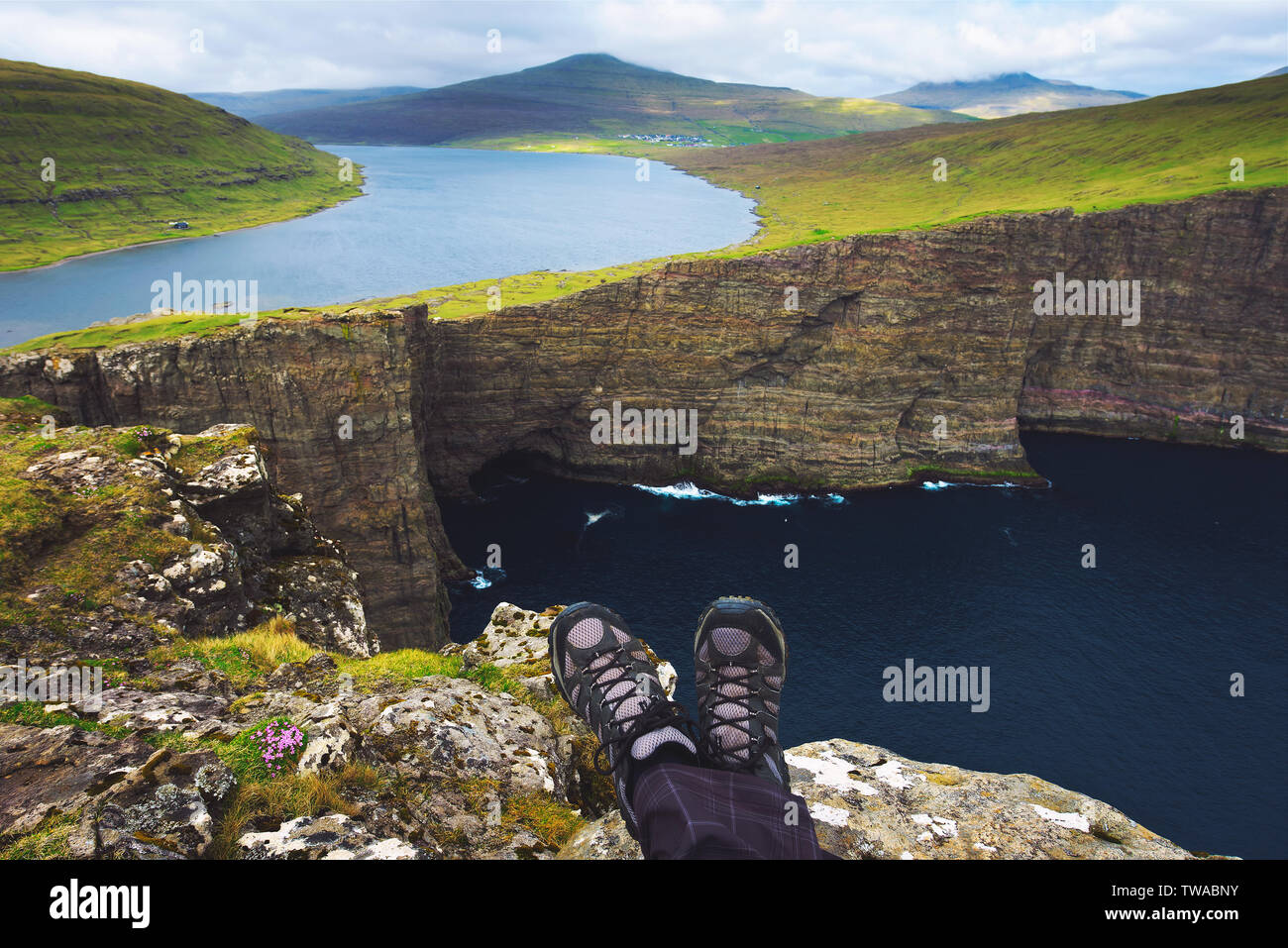 Beine der Wanderer sitzen auf einer Klippe über dem See Sorvagsvatn auf den Färöer Inseln Stockfoto