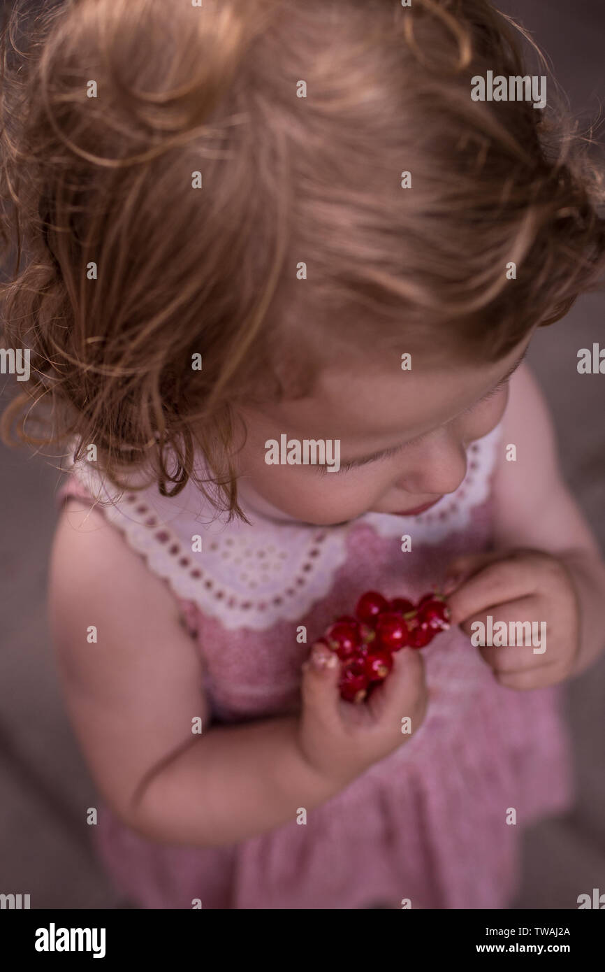 Kind genießen Sommer, Essen rote Beeren, tragen rosa retro Kleid Stockfoto
