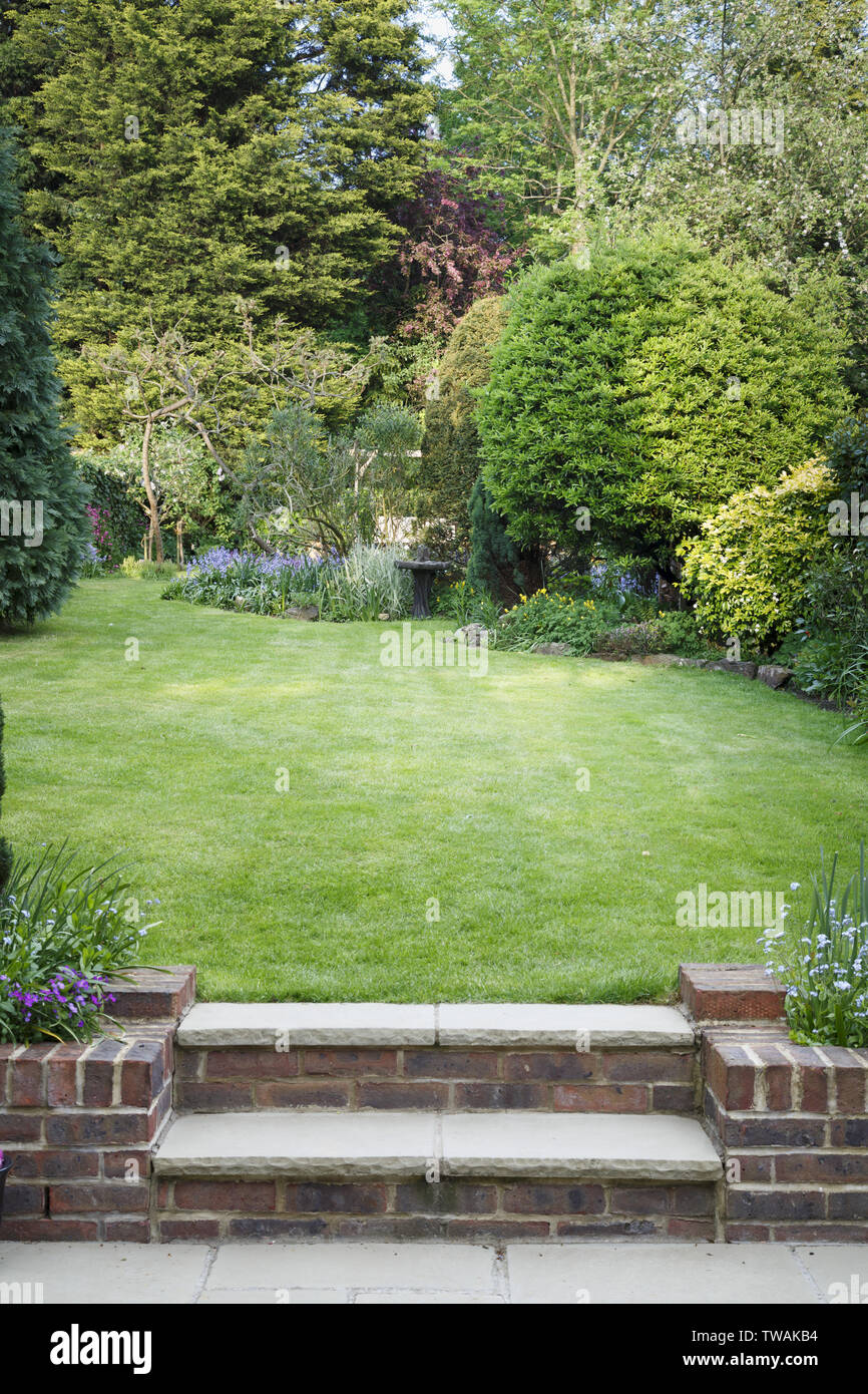 Terrassenförmig angelegten Garten mit Rasen, Schritte und Terrasse in England, Großbritannien Stockfoto