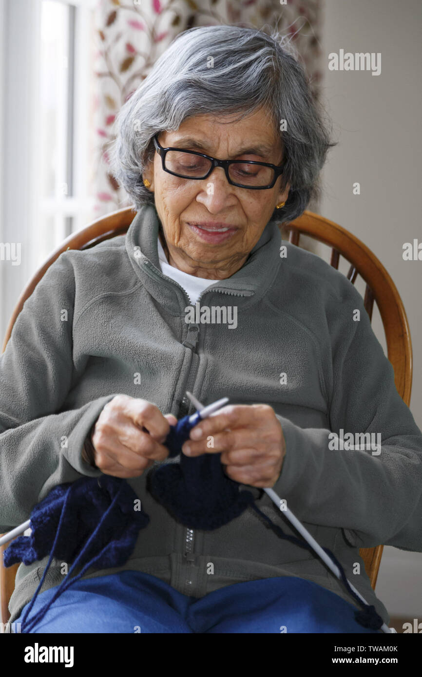 Senioren Frau Rentner der indischen Asiatische Ethnie sitzen, Stricken, glücklich in einem Hobby oder Zeitvertreib eingerückt Stockfoto