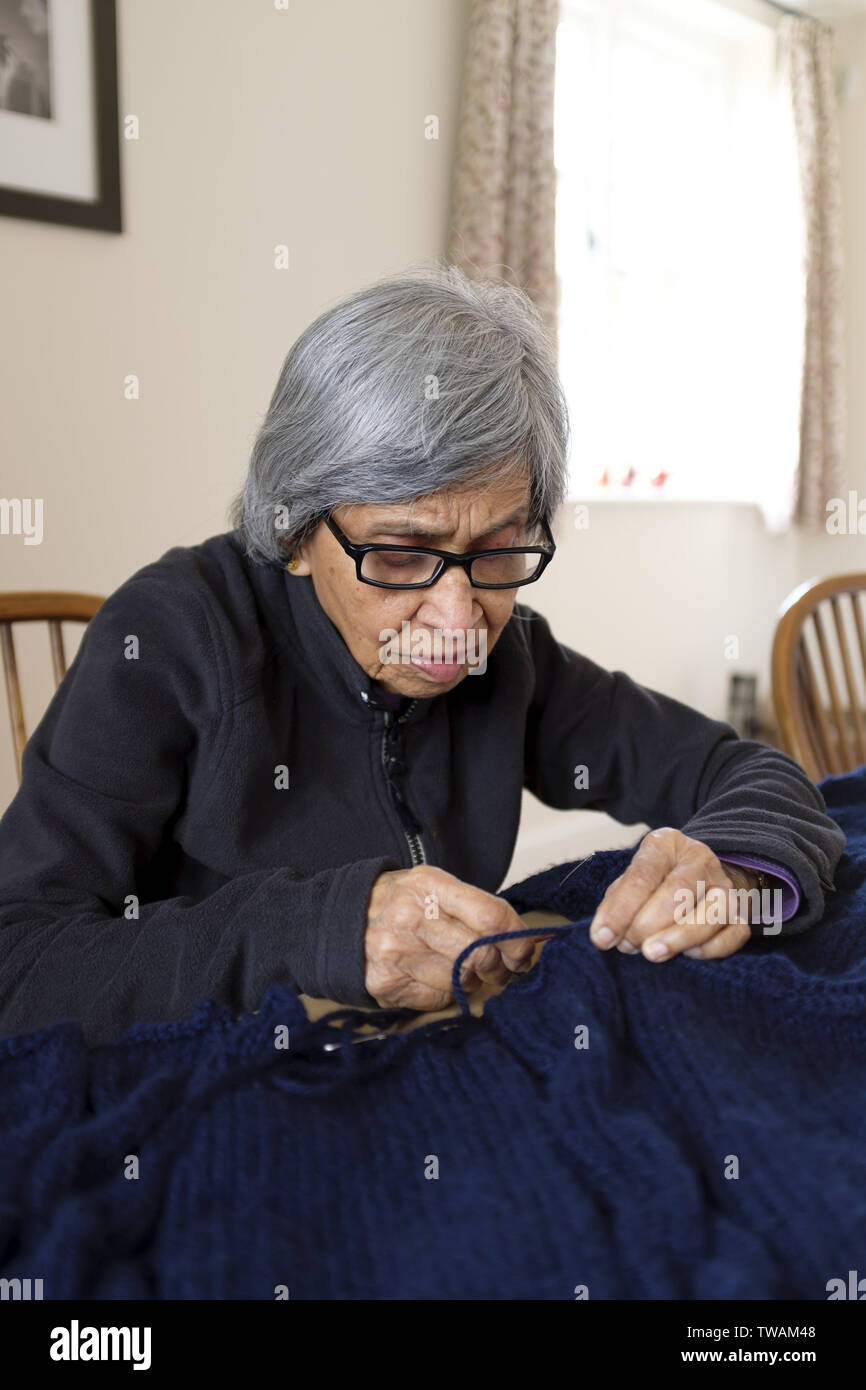 Eine alte Frau von Indische Asiatische Ethnie Stricken in einem Englischen home Stockfoto