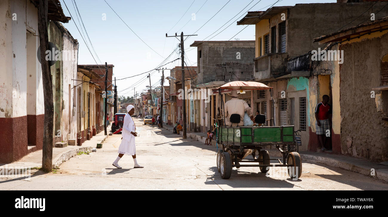 Eine Dame ganz in Weiß von der afro-kubanischen Religion Überqueren der Straße in Trinidad, Kuba. Stockfoto