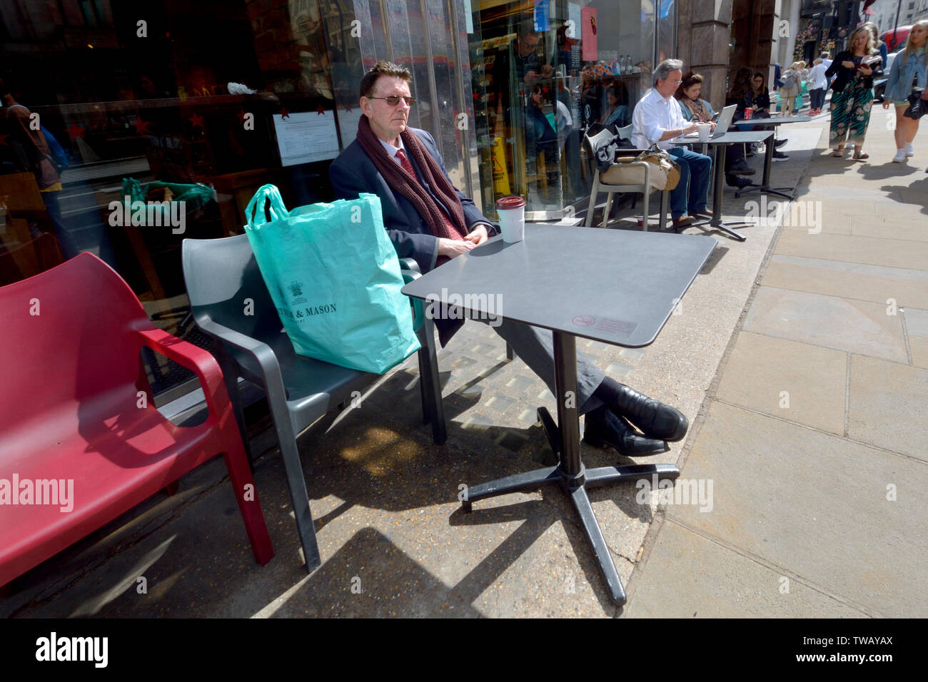 London, England, UK. Menschen bei outside cafe Tabellen in Piccadilly sitzen. Mann mit Fortnum & Mason Tragetasche Stockfoto