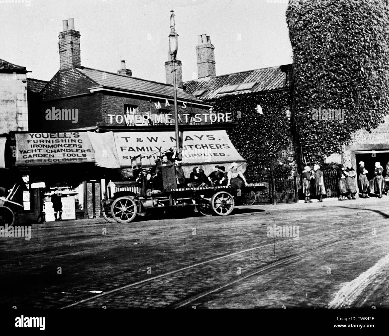 T&AMP;W Mays Turm Fleisch ausgeht, Shop's Familie Metzger, mit flachbett James Sutherland's Fahrzeug und Passagiere außerhalb und Youells Eisenwarenladen auf der Linken, Great Yarmouth, Norfolk. um 1910 s Stockfoto