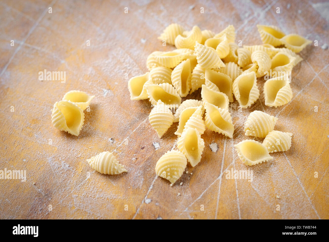 Frische Conchiglie Pasta auf einem Holztisch mit Mehl Stockfoto