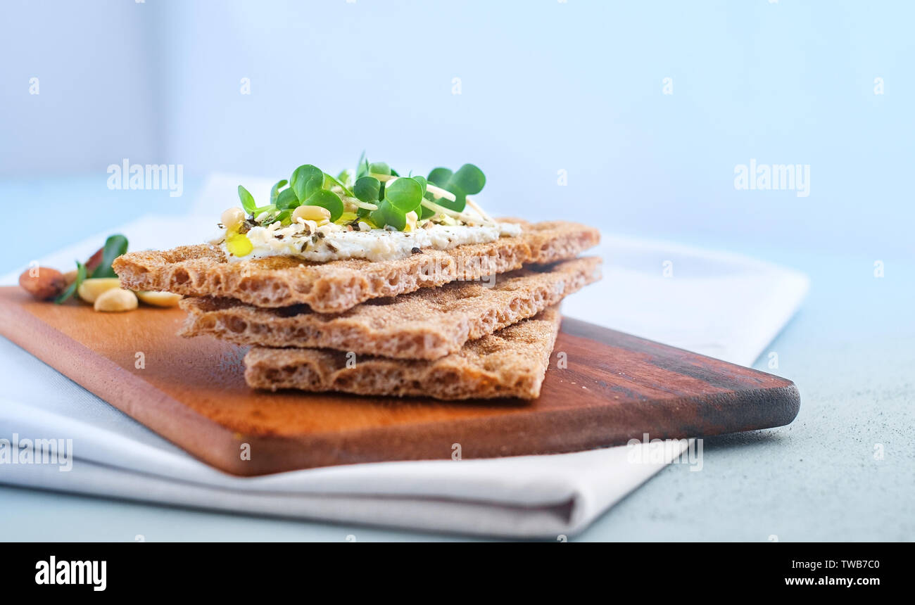 Knäckebrot mit Frischkäse und Kräutern auf einem Holzbrett, gesundes Frühstück. Gesundes Frühstück Stockfoto