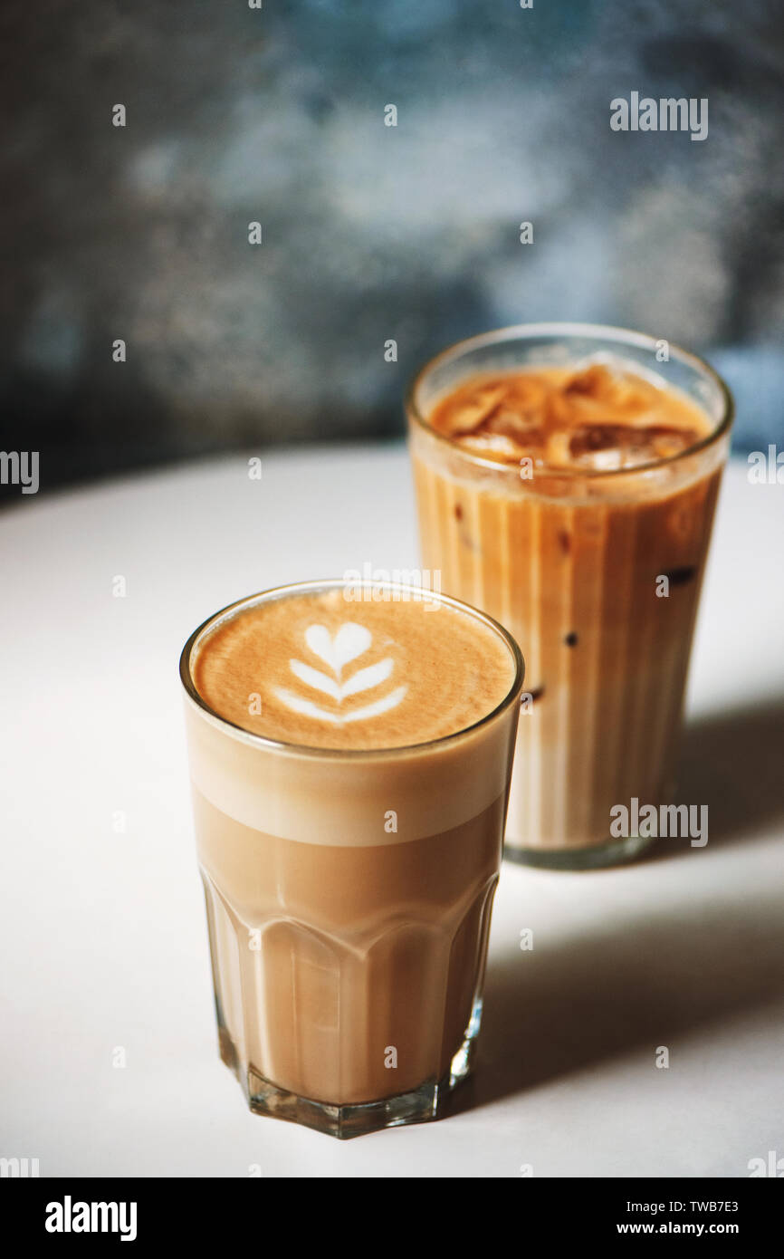 Latte und ice Latte in Kaffee Gläser auf weißem Tabelle im Cafe. Heiße und kalte Getränke. Stockfoto