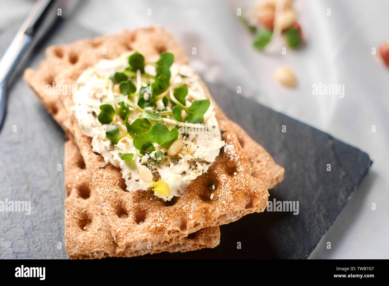 Knäckebrot mit Frischkäse und Kräutern auf einem Stein, gesundes Frühstück. Gesundes Frühstück Stockfoto