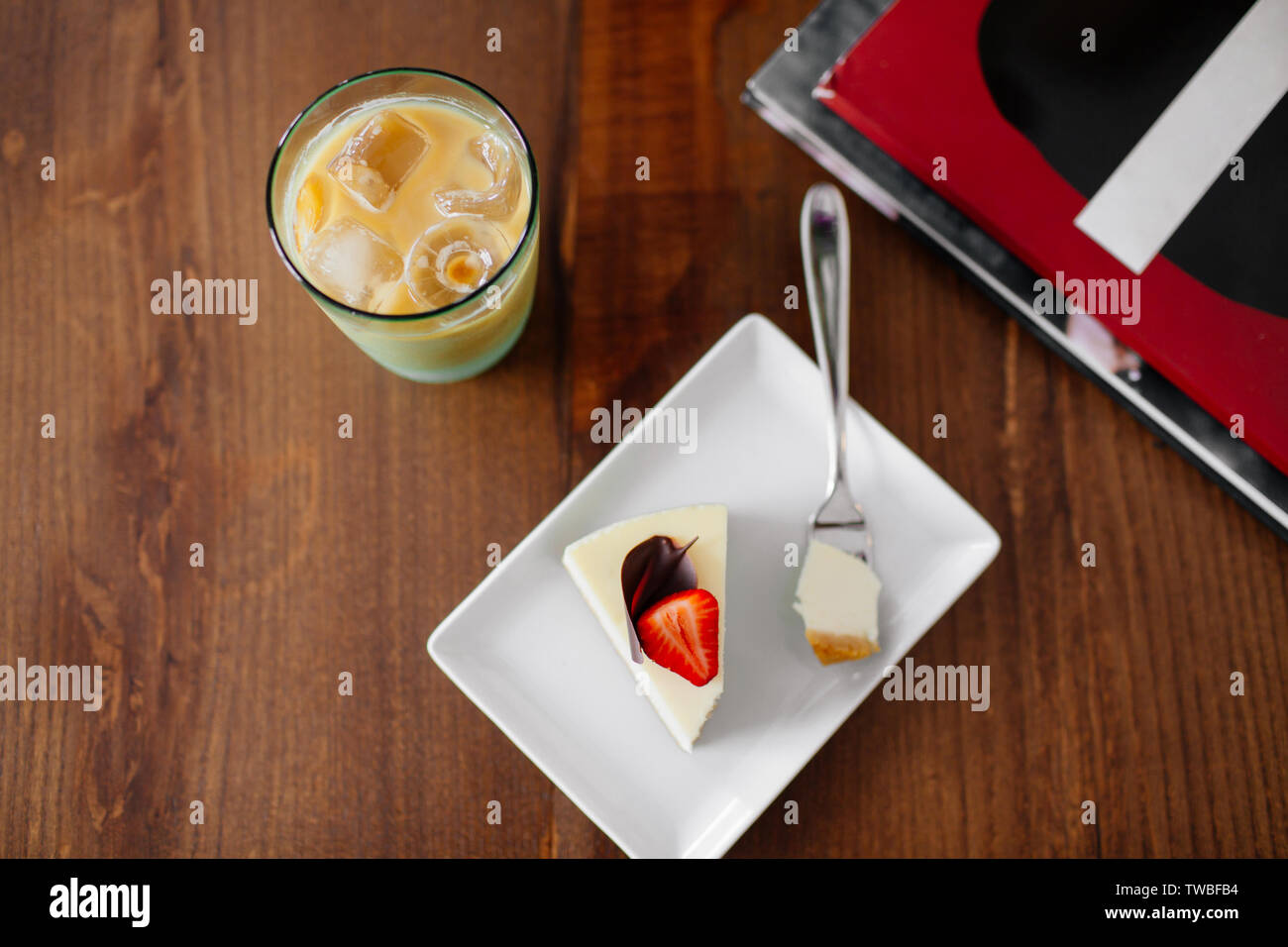 Ein Stück leckere luftig Kuchen mit Erdbeeren auf die Oberseite. Kalte frappe mit Eis neben, Ansicht von oben. Stockfoto