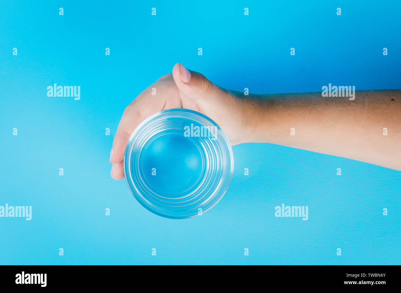Kinder Hand ein Glas reines Wasser auf einem blauen Hintergrund, kopieren Raum Stockfoto