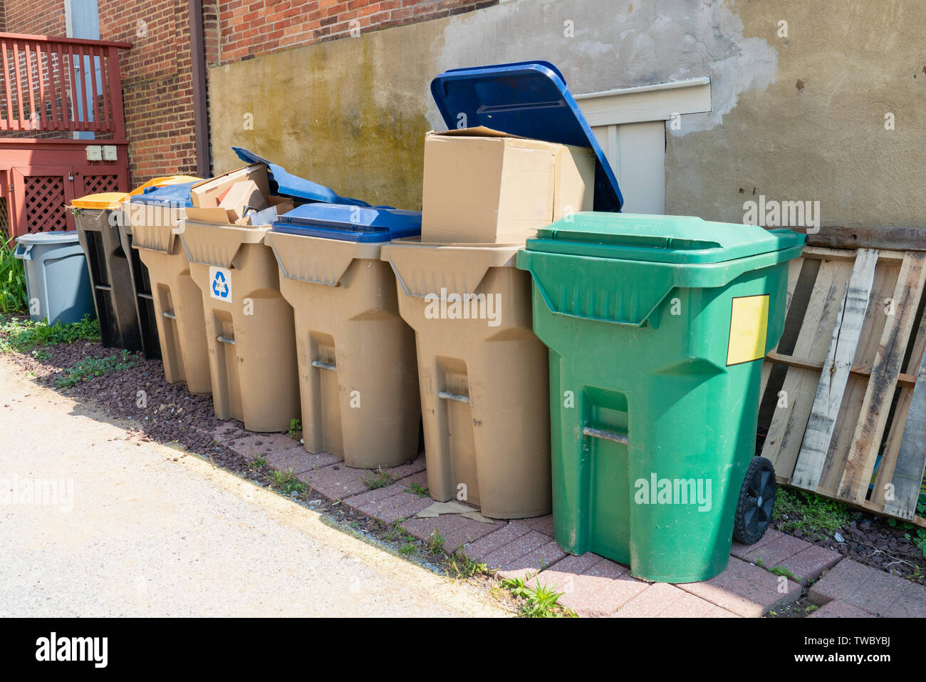 Viele Müll und Recycling bins geladen und wartet auf Abholung in einer Gasse weg Stockfoto