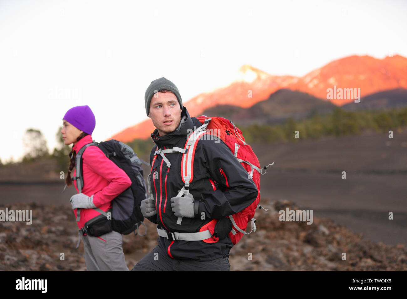 Wandern die Menschen auf den Berg. Wanderer Paar mit Rucksäcken im Freien in großer Höhe. Junger Mann, Wanderer im Fokus trekking bei Sonnenuntergang auf den Vulkan Teide, Teneriffa, Kanarische Inseln, Spanien. Stockfoto