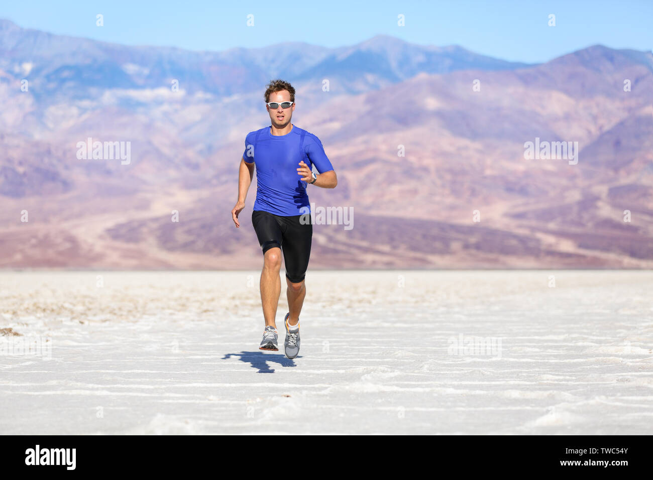 Laufender Mann-sprinten Sportler Läufer in die Wüste. Fit athletische Männlich fitness Modell in schnellen Sprint mit großer Geschwindigkeit in Richtung Kamera. Sport in erstaunlichen extreme Landschaft der Wüste. Stockfoto