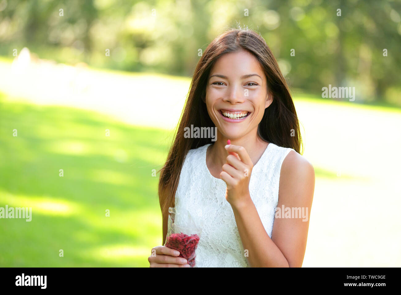 Frau essen Goji Beeren gesundes Essen Imbiss im Freien im Park. Gesunde Ernährung und Lebensstil mit schönen gemischten Rennen Asiatischen kaukasischen Frauen Mädchen Modell. 20 s Stockfoto