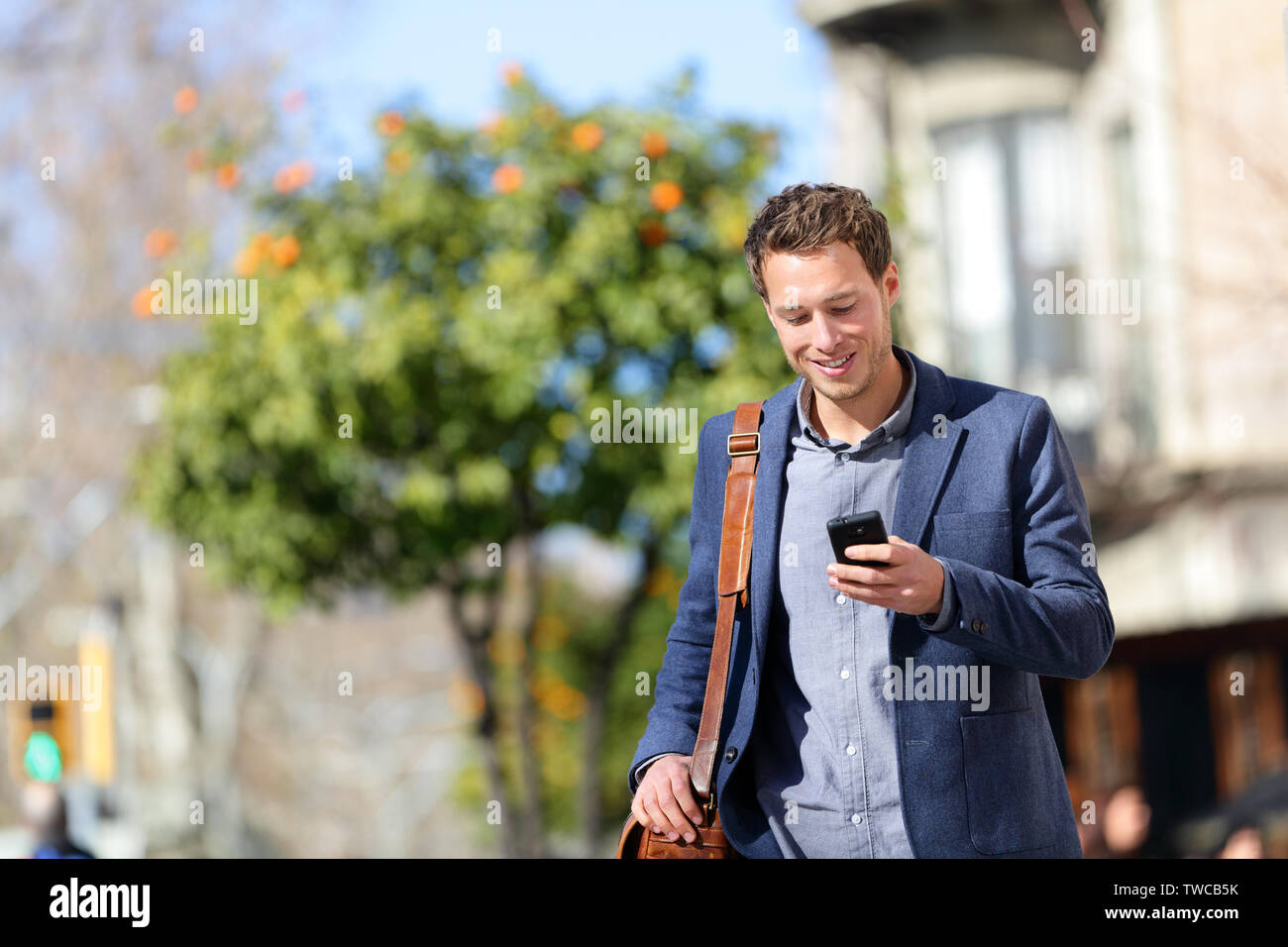 Young Urban professional Mann mit Smart Phone. Geschäftsmann holding Mobile Smartphone mit App sms sms-Nachricht tragen Jacke auf die Passeig de Gràcia, Barcelona, Katalonien, Spanien. Stockfoto