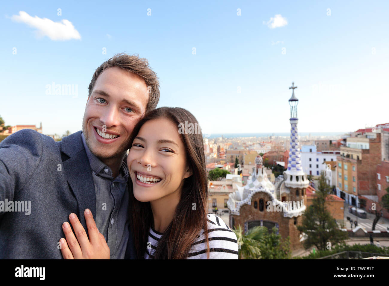 Happy Travel Paar im Park Güell, Barcelona, Spanien. Schöne junge Gemischtrassiges Paar an der Kamera unter selfie Lächeln freuen sich über Europa Urlaub Reise suchen. Asiatische Frau, kaukasische Mann. Stockfoto