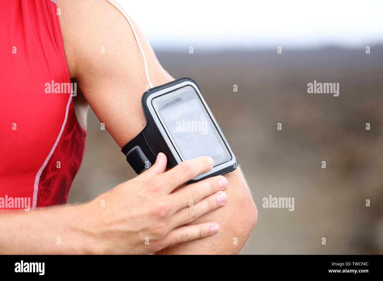 Smart Phone läuft Musik Nahaufnahme - männliche Läufer Musik Einstellungen auf Armband für Smartphone. Passen Mann fitness Modell außerhalb in Rot sportliches Outfit arbeiten. Stockfoto