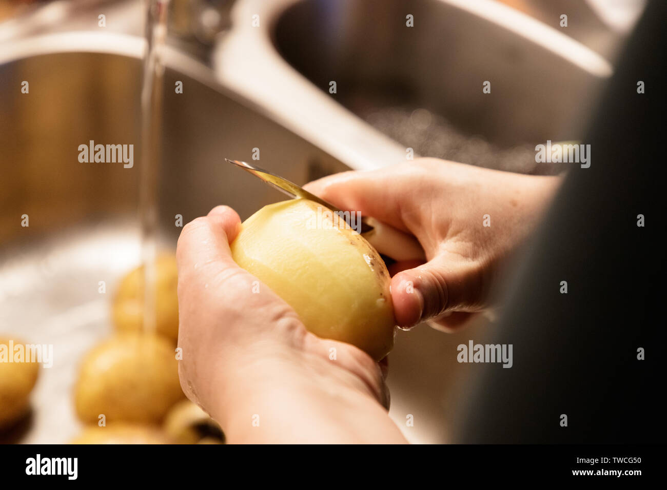 Frau Schälen von Kartoffeln über ein Spülbecken closeup Stockfoto