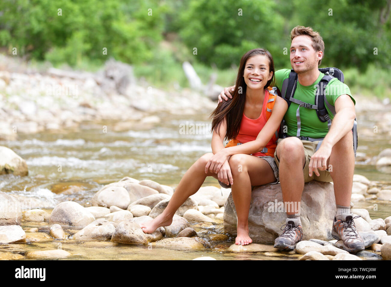 Wandern Paar - Wanderer im Zion National Park. Junge Frau und Mann Wanderer sitzen durch Wasser des Flusses Creek genießen Blick lächelte glücklich. Junges Paar trekking, entspannend nach der Wanderung, Utah, USA. Stockfoto