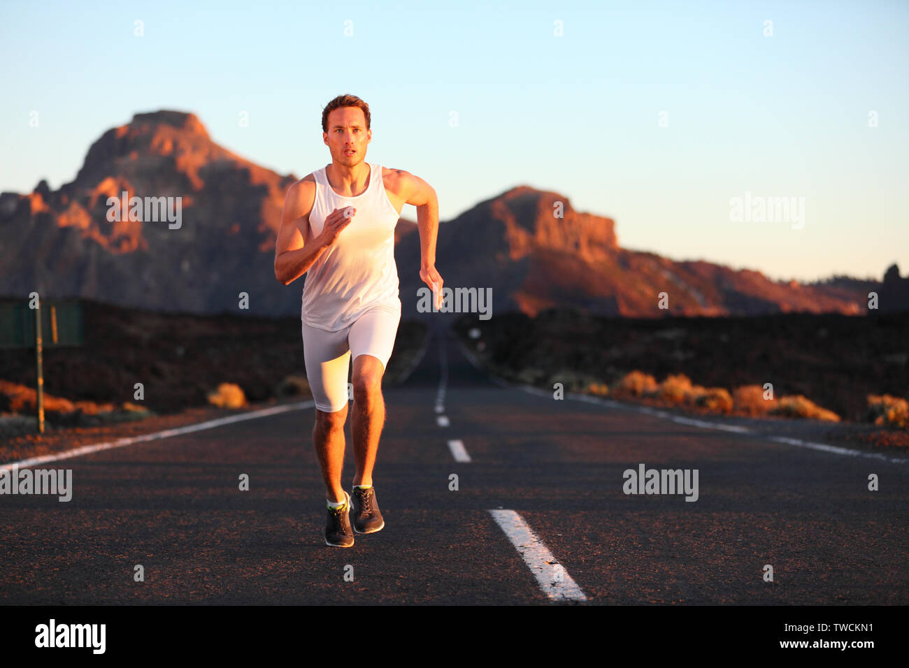 Athleten laufen sprintet bei Sonnenuntergang auf der Straße. Männliche Läufer Ausbildung in der Berglandschaft in der Nacht. Passen junge muskulöse Fitness Sport Modell in seiner 20. Stockfoto