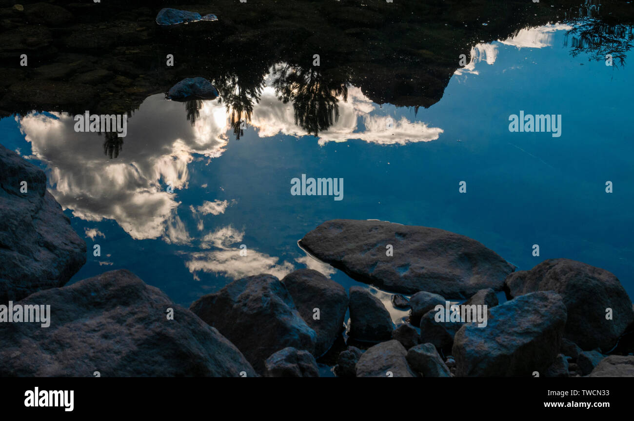 Reflexionen von Himmel und Wolken am Ufer mit Steinen in das klare Wasser des Flusses Meliquina in Neuquén, Patagonien Argentinien. Stockfoto