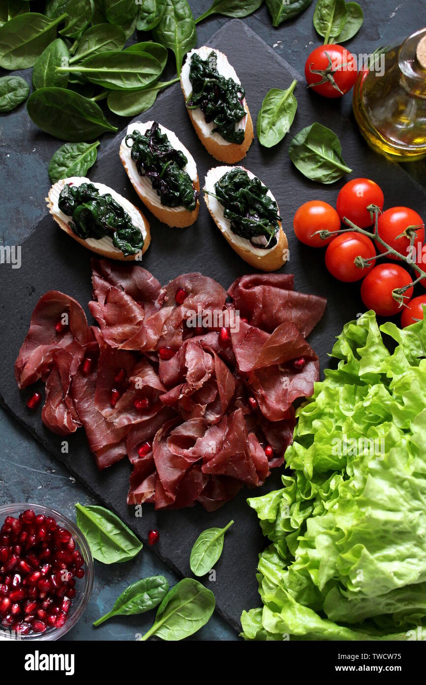 Gesunde Ernährung Essen Konzept. Bügeleisen auf das Essen. Die bruschetti mit Spinat, Bresaola und Granatapfel. Ansicht von oben mit der Kopie. Stockfoto