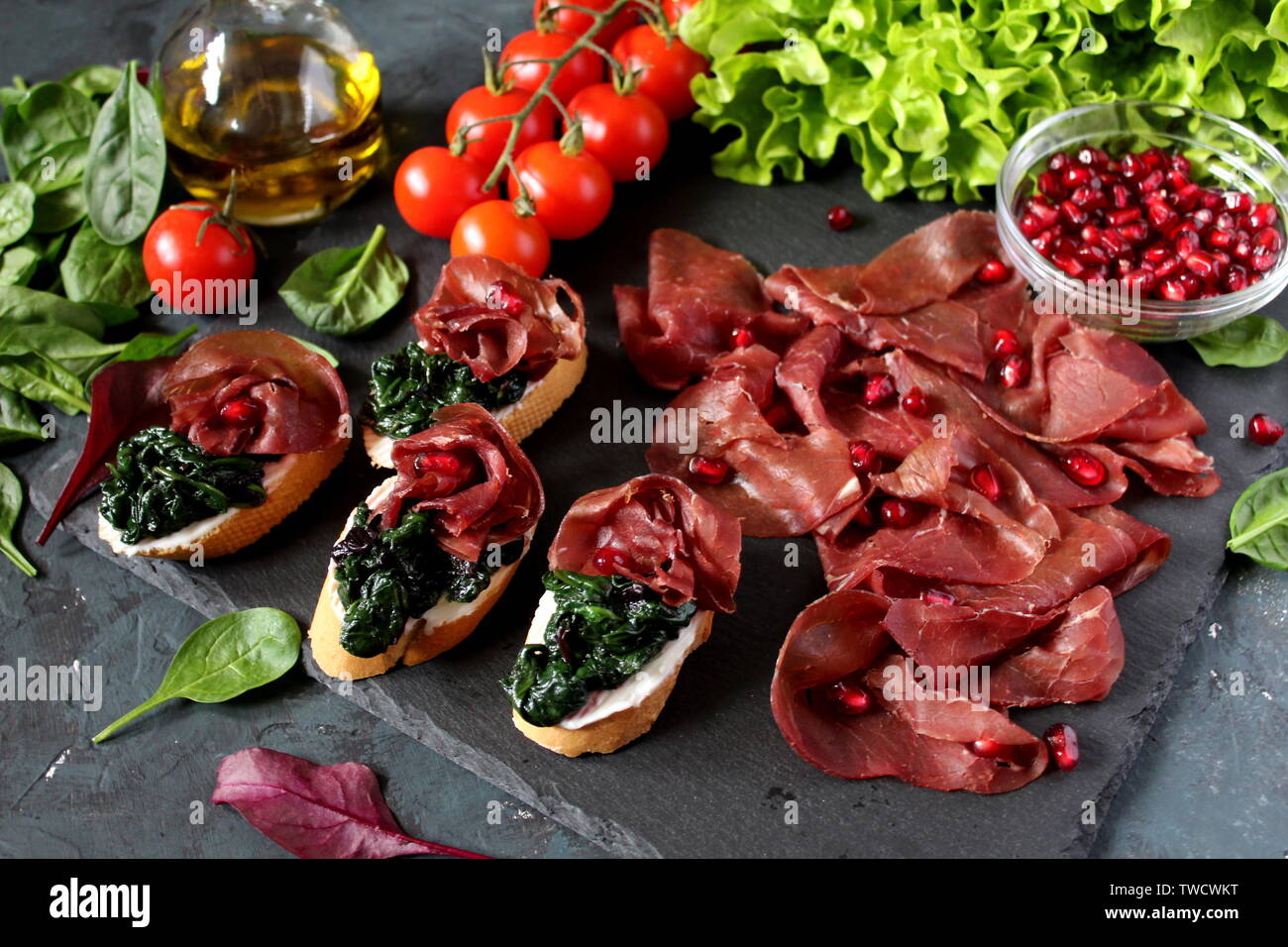 Gesunde Ernährung Essen Konzept. Bügeleisen auf das Essen. Die bruschetti mit Spinat, Bresaola und Granatapfel. Ansicht von oben mit der Kopie. Stockfoto