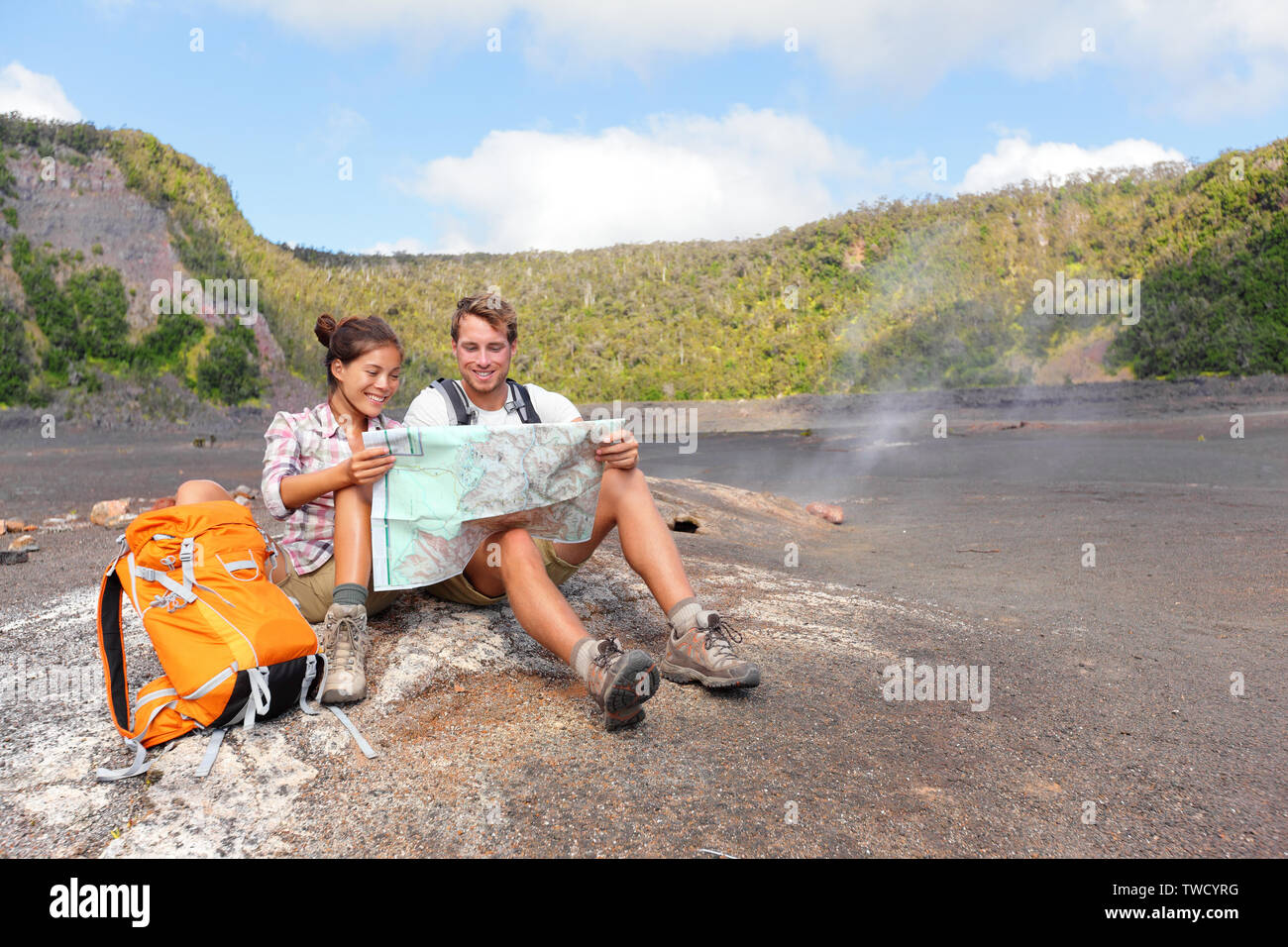 Paar Wandern auf Vulkan auf Hawaii bei Karte suchen. Glückliche junge Mann und Frau entspannende, schöne vulkanische Landschaft Natur auf Big Island auf Hawaii Volcanoes National Park, USA brechen. Stockfoto