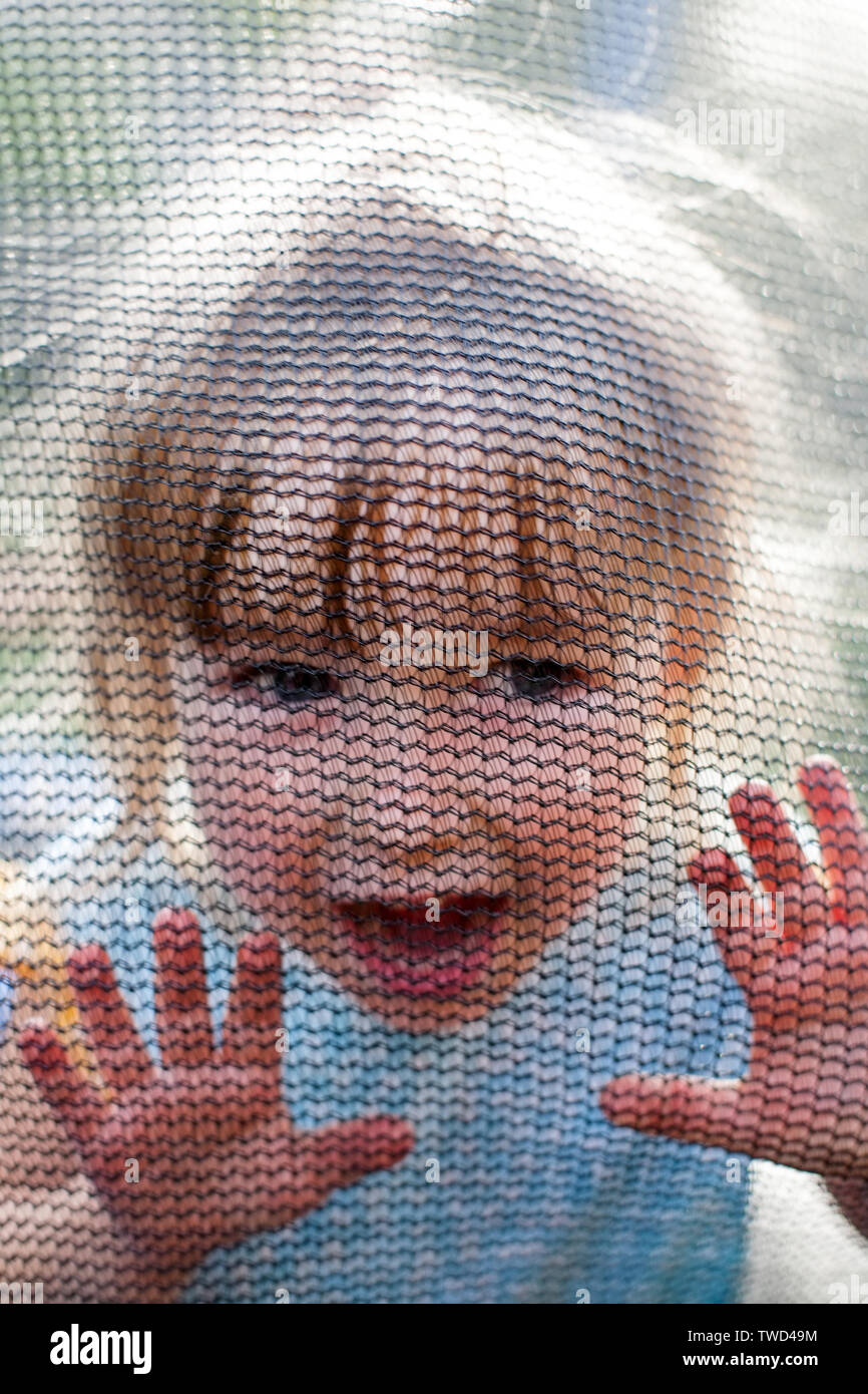 Schreiende kleinkind Mädchen hinter Trampolin netz Gesicht Nahaufnahme Stockfoto