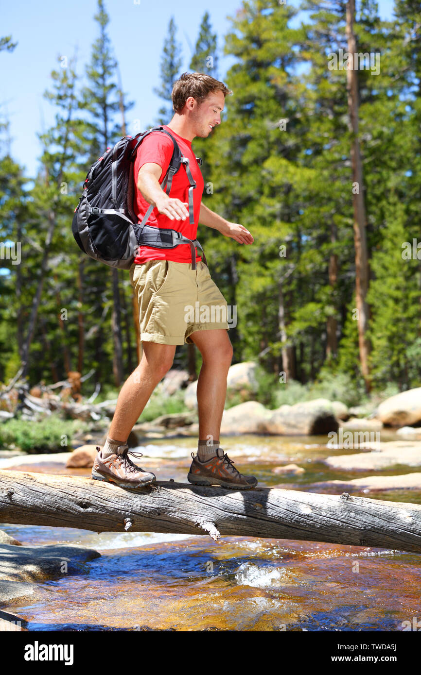 Wandern mann Fluß zu Fuß in das Gleichgewicht gefallenen Baumstamm im Yosemite Landschaft Natur Wald. Gerne männliche Wanderer Trekking im Freien im Yosemite National Park, California, United States. Stockfoto