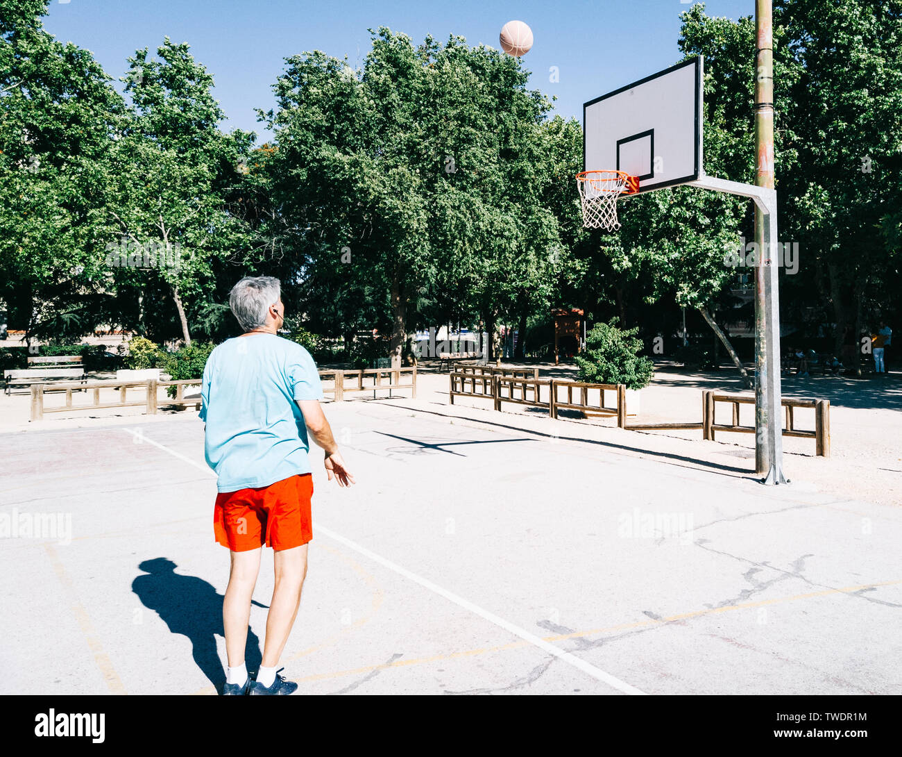 Alter Mann spielen und Coaching Warenkorb allein in einem Basketballplatz Stockfoto