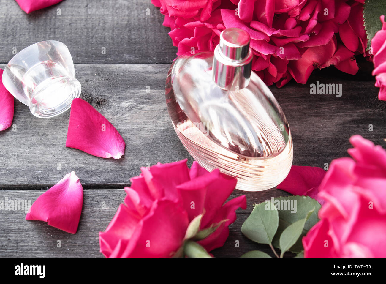 Flasche Frauen Düfte mit roten Rosen auf dem Hintergrund der dunklen Holz. Aromatherapie Stockfoto