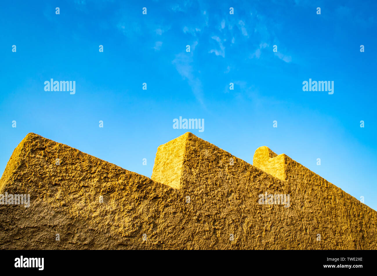 Gelbe Steinmauer in geometrischen Formen auf blauem Himmel Hintergrund. Von Muscat, Oman. Stockfoto