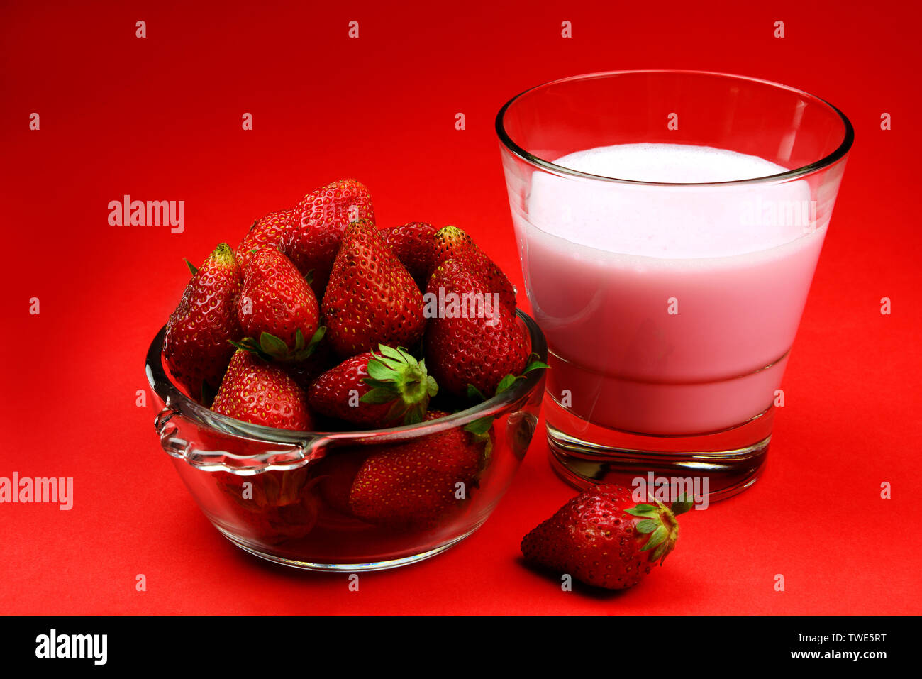 Frische, Reife und saftige Erdbeere Obst in einer Schüssel mit einem Glas Erdbeer shake oder smoothy Stockfoto