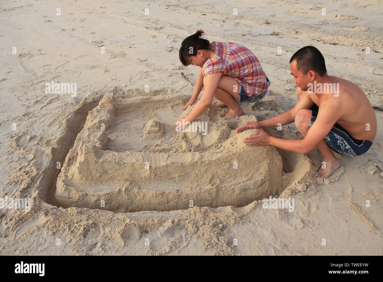 Paar machen Sandburg am Strand Stockfoto