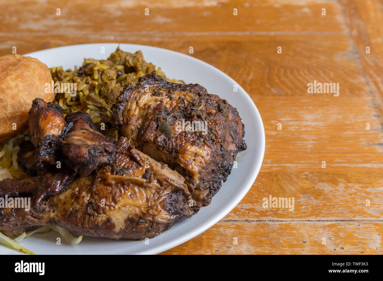 Die jamaikanische Essen. Traditionellen jamaikanischen Ziege, Jerk Chicken Curry und gebratene Knödel mit Reis und Erbsen Stockfoto