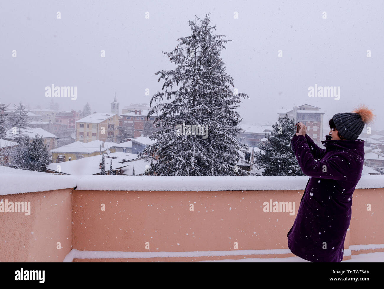 Frau draußen auf Balkon machen Fotos der schneebedeckten malerische Aussicht während der schneesturm in Avezzano Region Abruzzen in Italien. Stockfoto