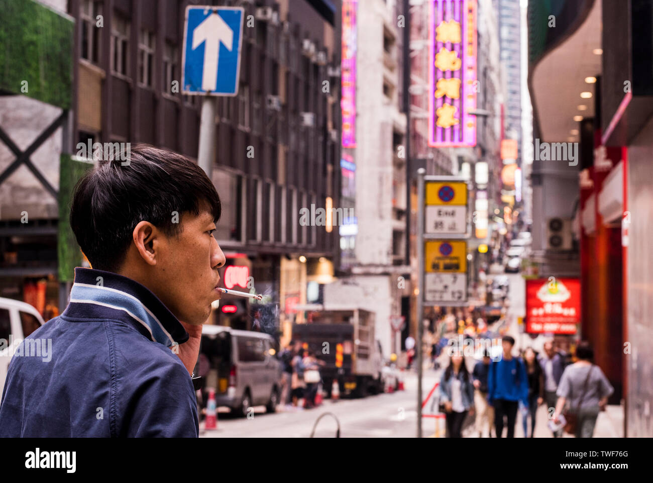 Mann rauchen Zigarette und belebten Straße mit Smartphone in der Nähe bis in Kowloon in Hong Kong. Stockfoto