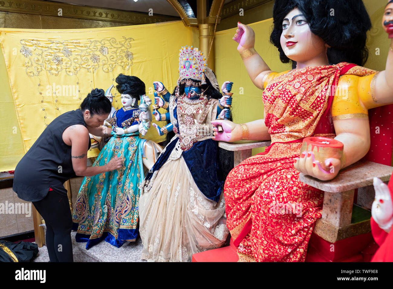 Als Teil einer Danksagung Ritual, eine fromme Frau entworfen und installiert neue Kleidung auf dem Tempel Statuen von Gottheiten. In Ozone Park, Queens, NYC Stockfoto