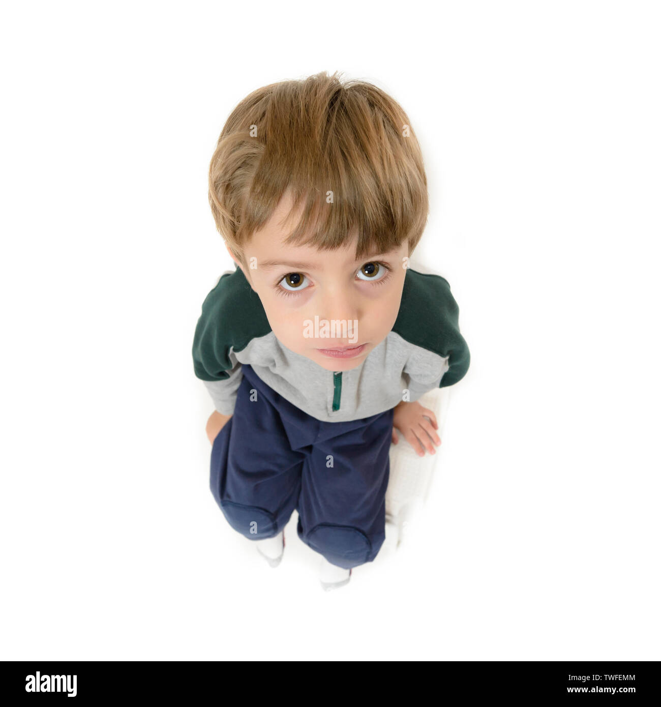 Süße Lonely Boy auf einem Stuhl und sah hilflos, auf weissem isoliert Stockfoto
