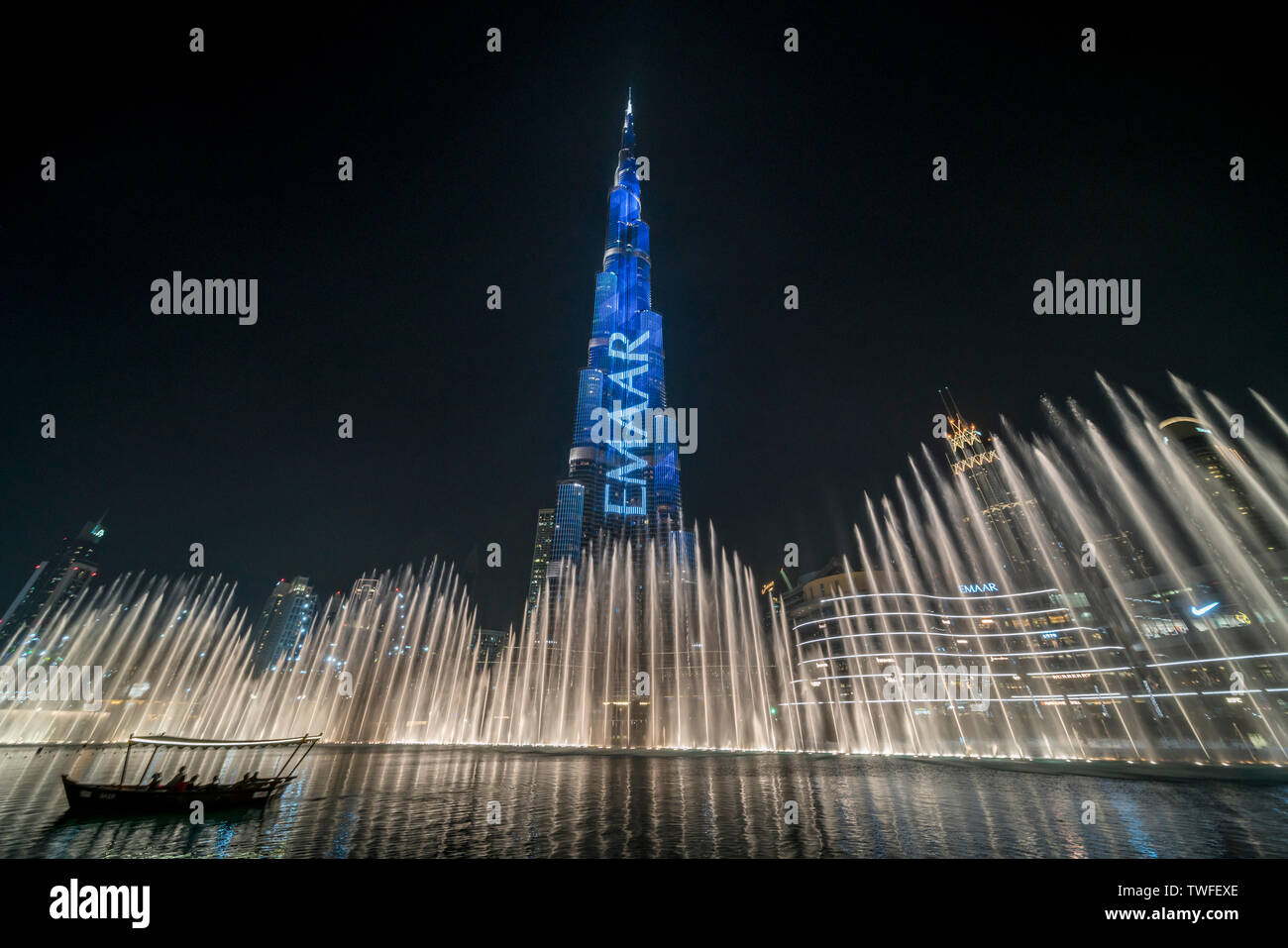 Die Dubai Fountain Tänze unter dem beleuchteten Burj Khalifa als Passagiere auf dem Boot beobachten. Stockfoto