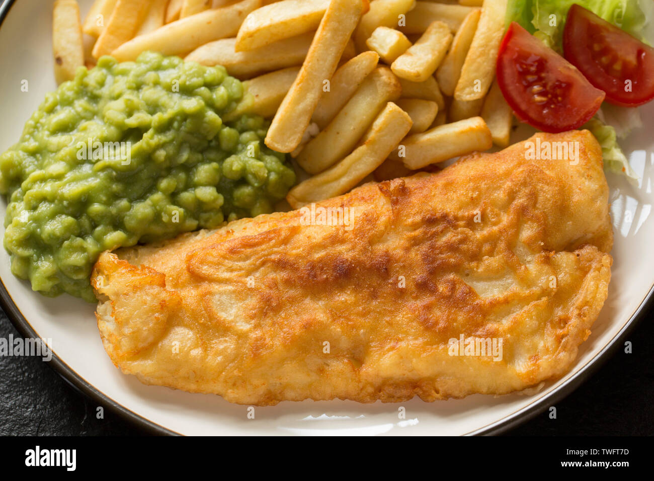 Ein seelachsfilet, Pollachius pollachius, dass in hausgemachter Teig beschichtet ist und frittiert und mit Erbsenpüree und Chips serviert. Der Pollack war Stockfoto