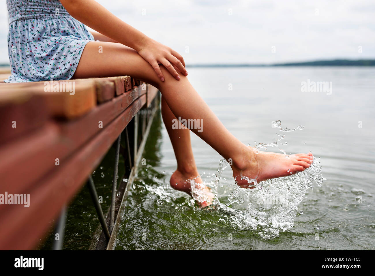 Mädchen am Rande eines Dock kicking Wasser sitzen, Vereinigten Staaten Stockfoto